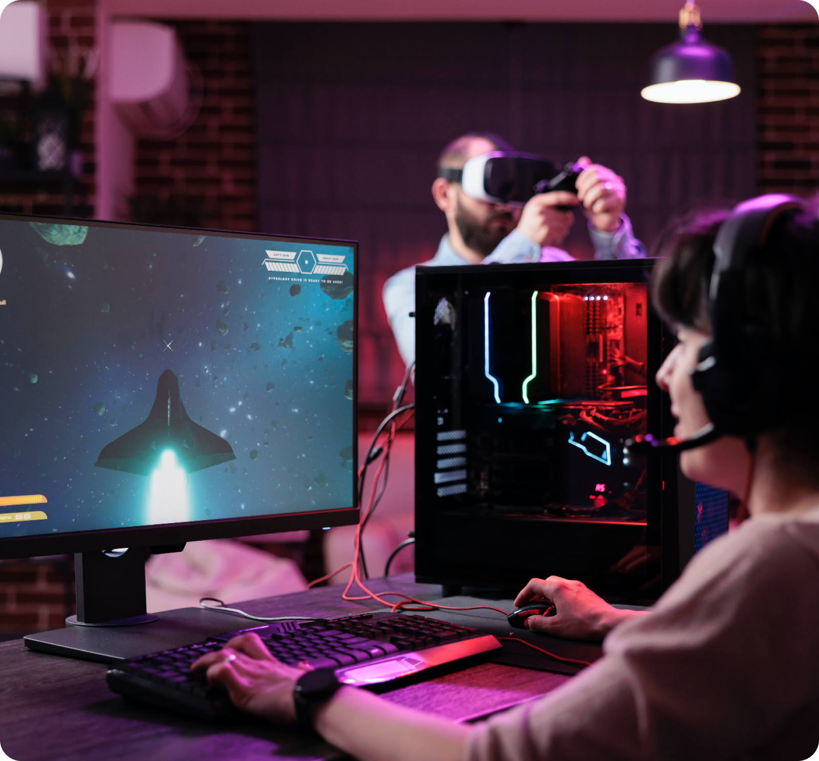 Person gaming with headset, computer, and VR headset, displaying language options on screen.