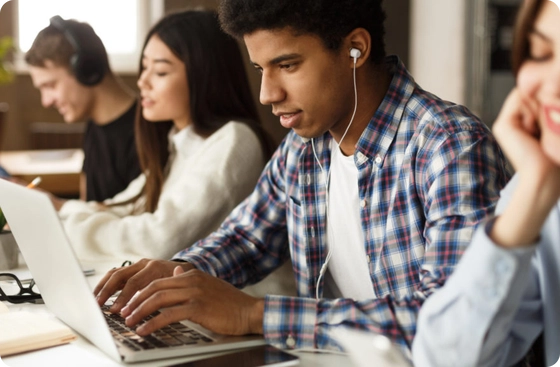 Two women laughing together while working on laptops in a cozy cafe setting.