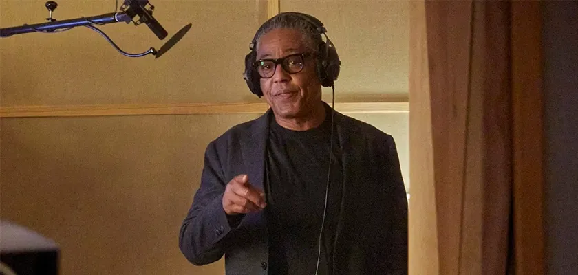 Der Schauspieler Giancarlo Esposito, bekannt aus den Serien Breaking Bad und The Mandalorian, steht mit Kopfhörer in einem Aufnahmestudio und zeigt auf die Zuhörenden. Links von ihm ist ein Mikrofon zu sehen.