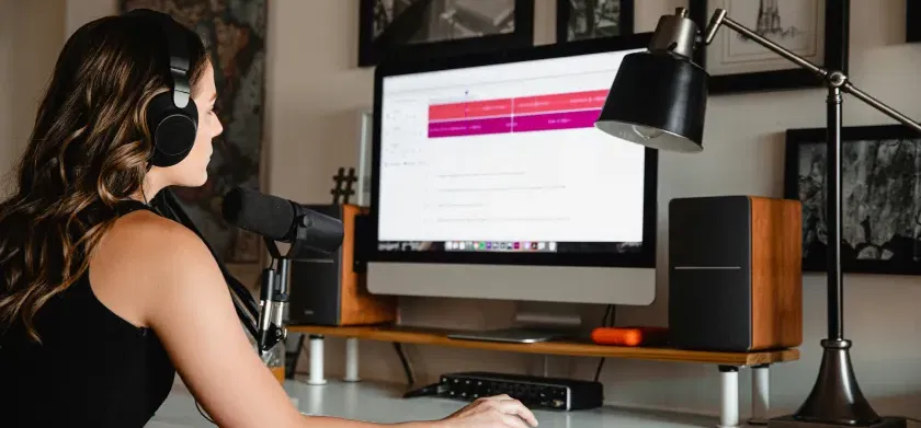 Woman with a headset working on a white desk on a computer