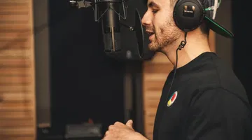 Un homme enregistre sa voix avec un microphone dans un studio.