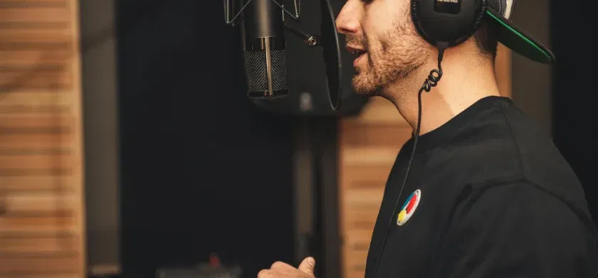 Un homme enregistre sa voix avec un microphone dans un studio.