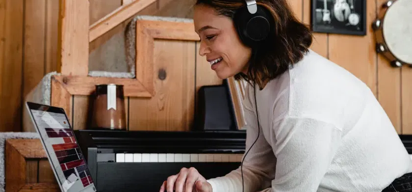 A woman wearing headphones uses a laptop to decide on assistive technology: ReadSpeaker Text to Speech, free TTS, or both?