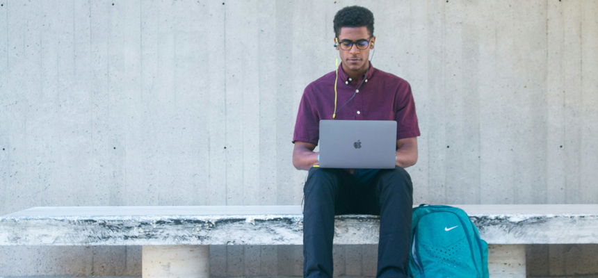 A man sitting on a bench with a laptop.