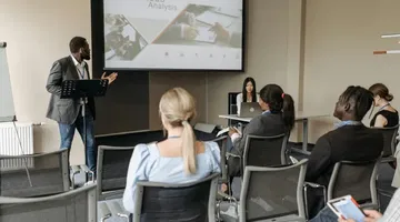 Man in black blazer having a presentation in front of employees demonstrating universal design for learning (UDL) principles for workplace training