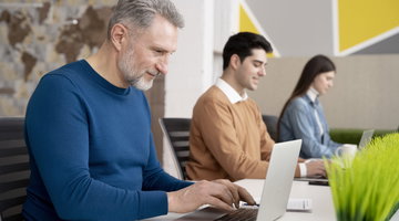 Three people are in front of their laptops.
