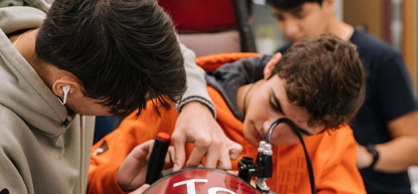 Two male apprentices working side by side, on race car mechanics.
