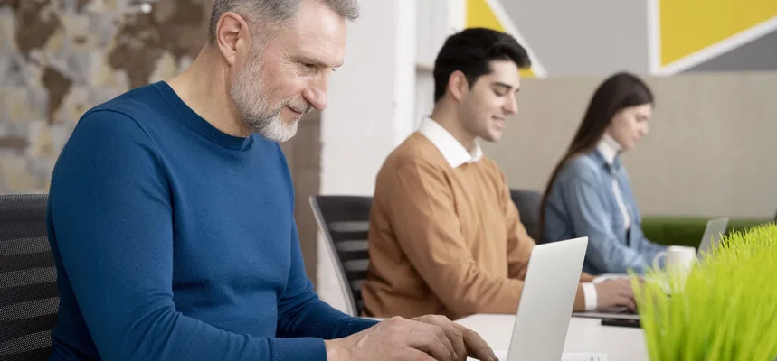 Três pessoas estão em frente aos seus laptops.