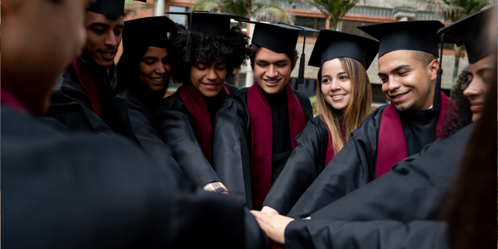 Um grupo de estudantes do ensino superior estava em semicírculo, celebrando a formatura. Eles vestiam becas e capelos pretos.